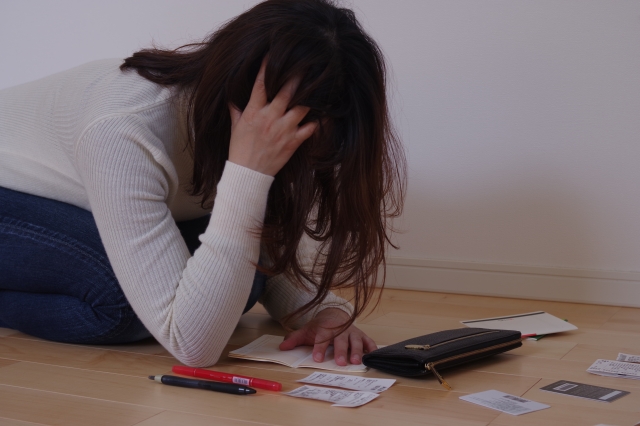 お金を手に頭を抱える。箕面市で債務整理の無料相談が弁護士にできます